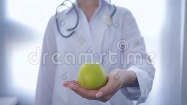 <strong>营养学家</strong>手里拿着绿苹果，伸展成相机，建议健康饮食，不集中注意力